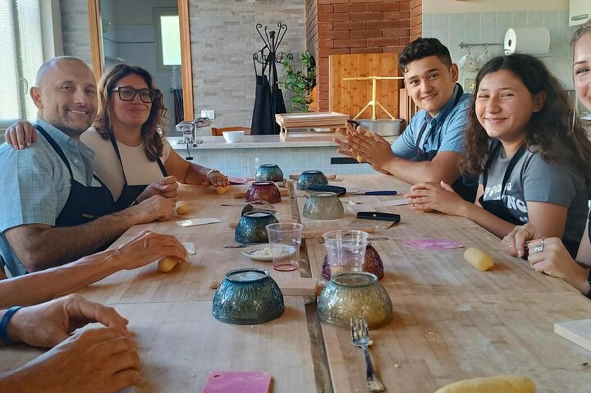 μια ομάδα ανθρώπων που κάθονται γύρω από ένα τραπέζι με κεραμικά