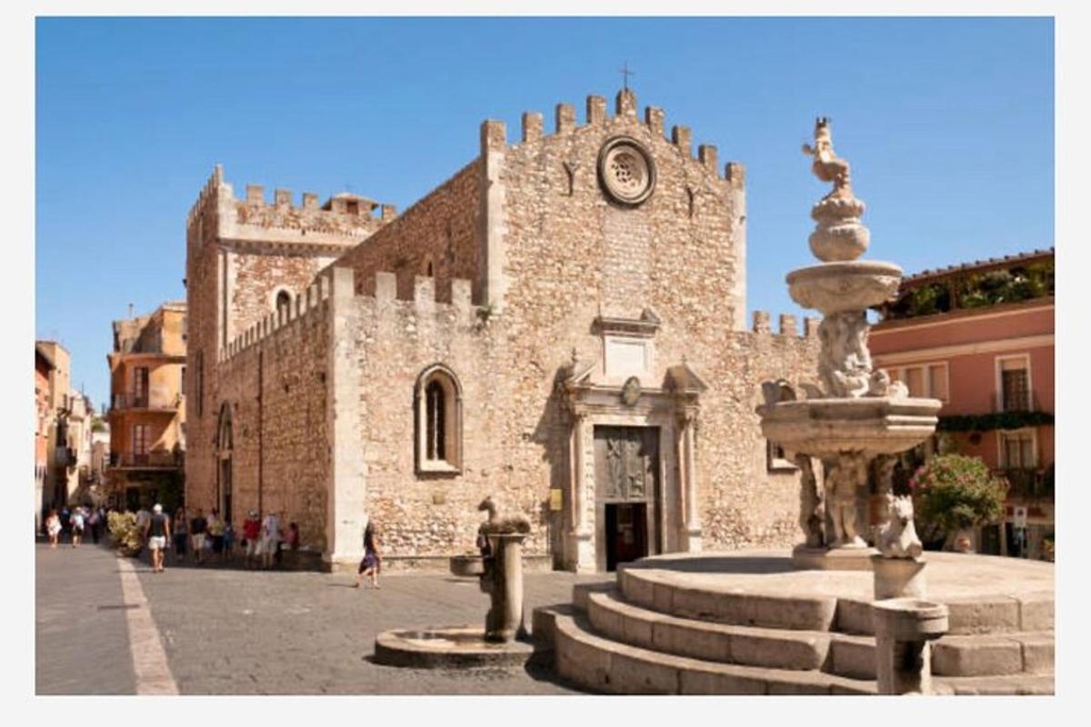 un edificio in pietra con una torre dell'orologio e una fontana