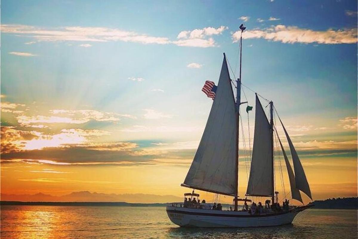 a sail boat in the water with the sun setting