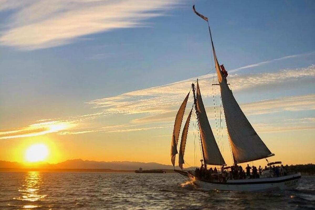 a group of people on a sail boat in the water at sunset