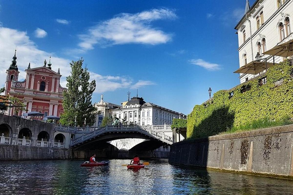 dwie osoby w kajakach na rzece z mostem