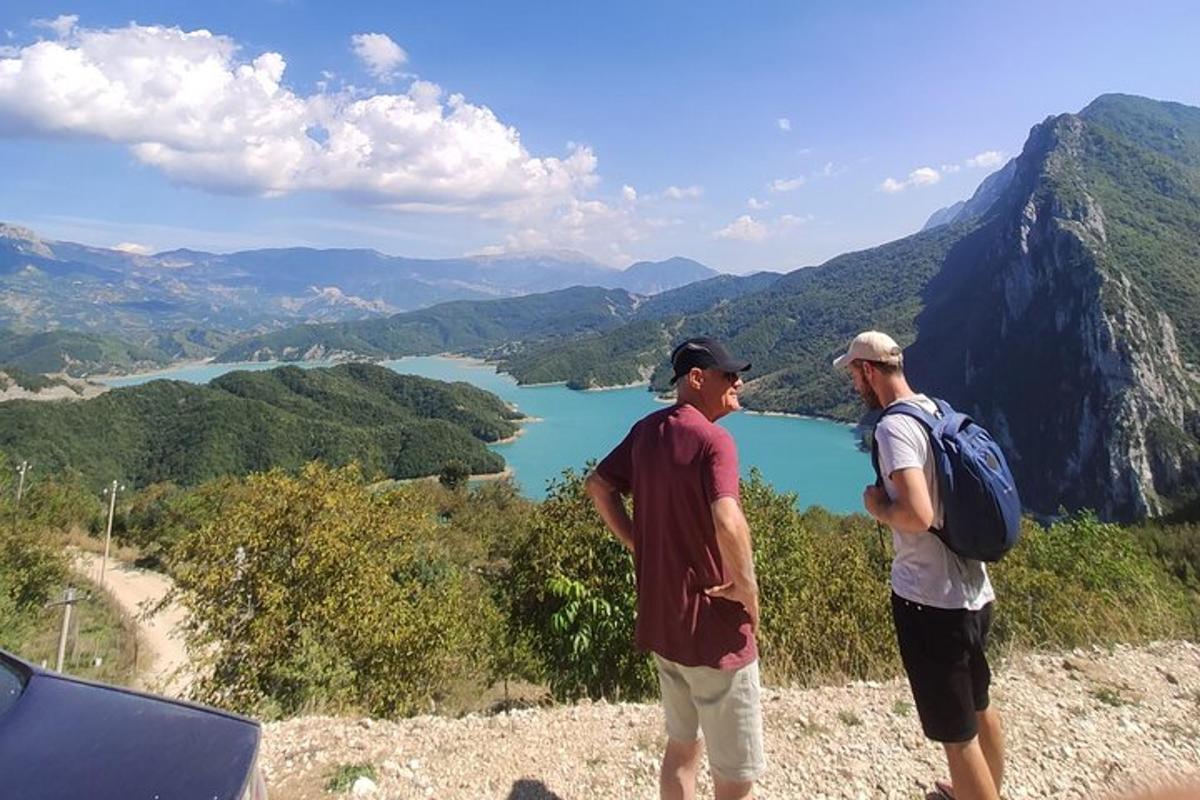Dos hombres de pie en la cima de una montaña con vistas a un lago.