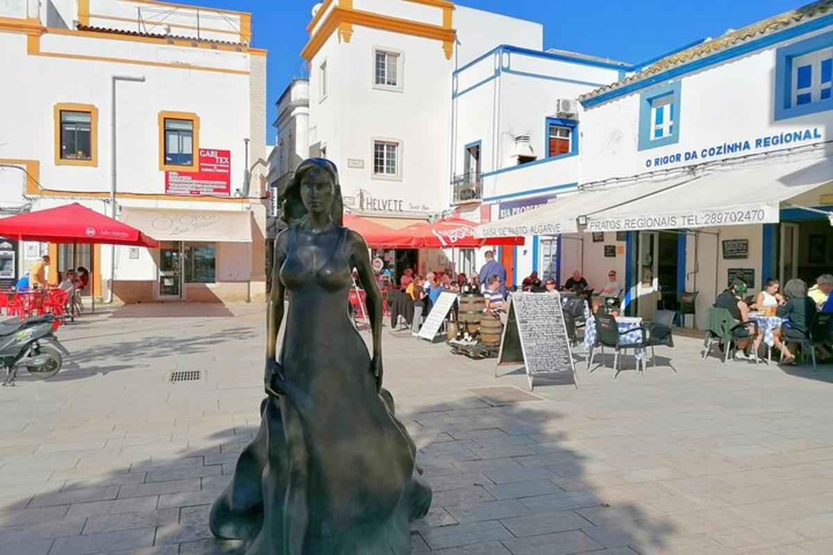 Una estatua de una mujer con un vestido en una calle.