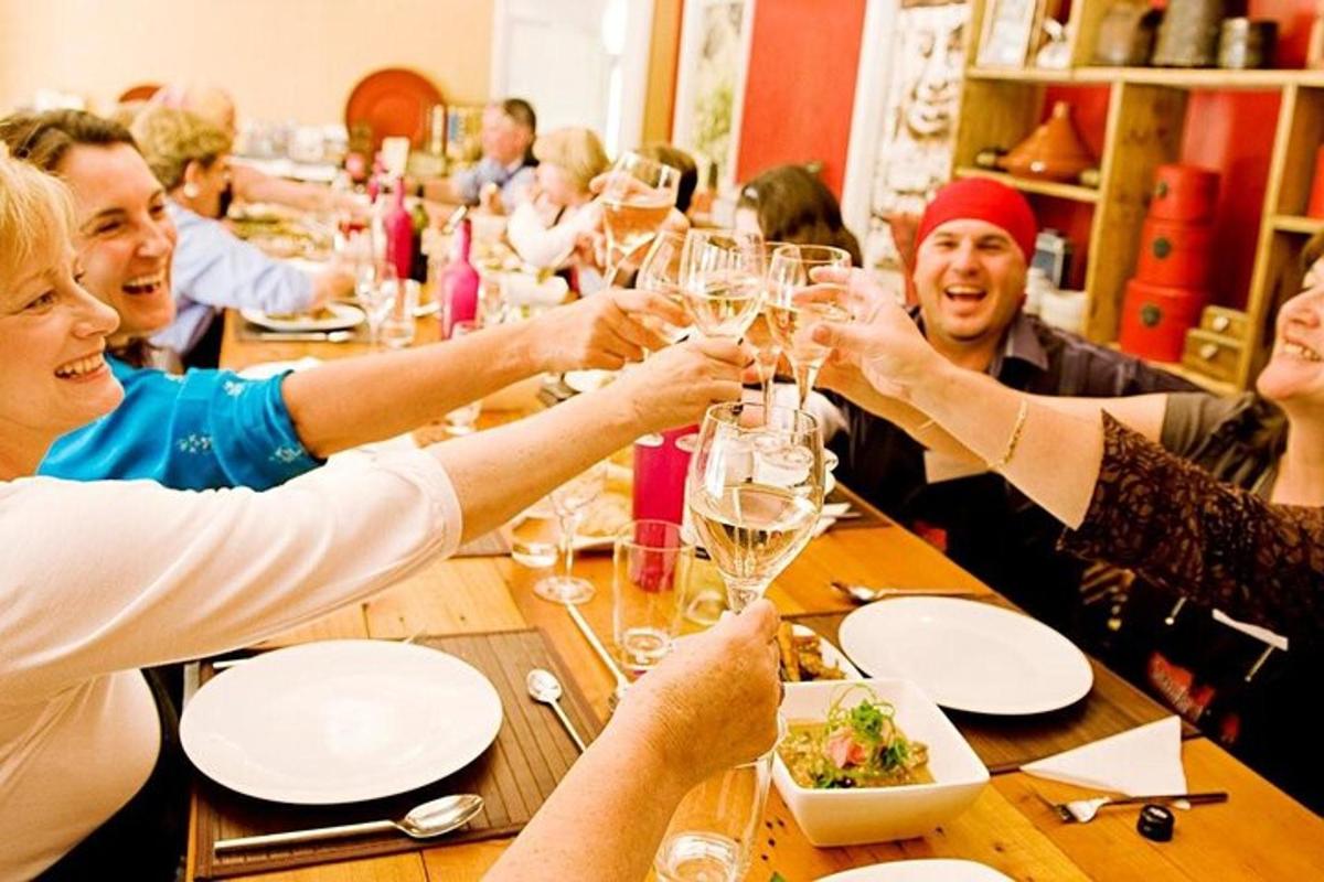 skupina ljudi, ki sedijo okoli mize in pijejo vino