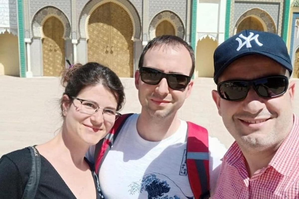 bir binanın önünde fotoğraf çektiren üç kişi