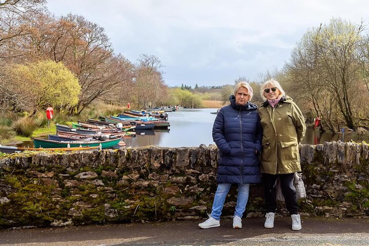 due donne in piedi accanto a un muro di pietra vicino a un fiume