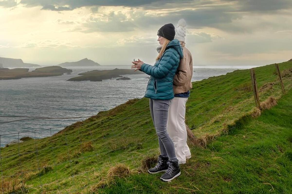 un uomo e una donna in piedi su una collina che domina l'oceano