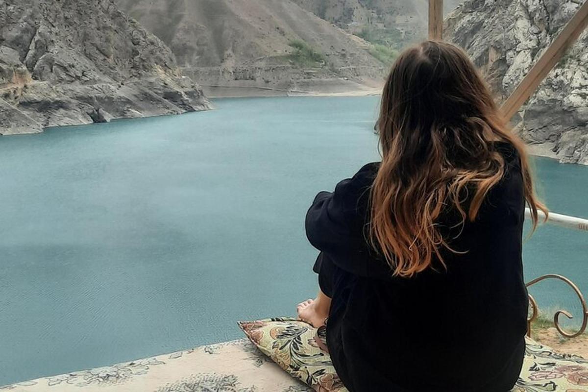 a woman sitting on a bed looking out at a lake