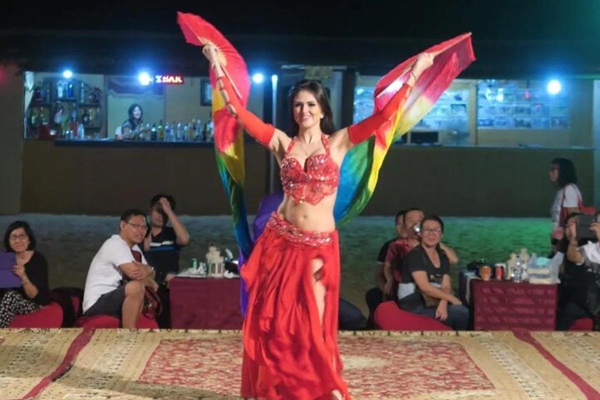 μια γυναίκα που στέκεται σε μια πίστα χορού με τα χέρια ψηλά