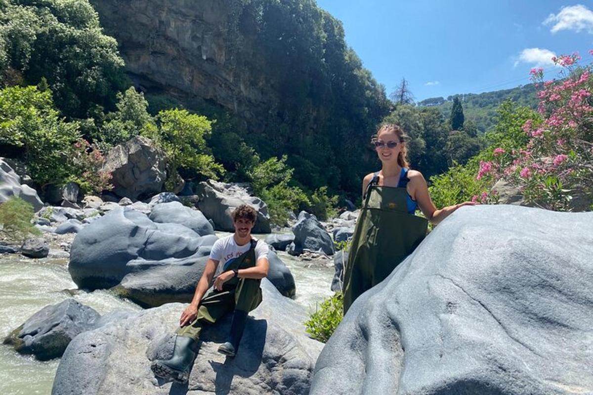un homme et une femme debout sur des rochers au bord d'une rivière