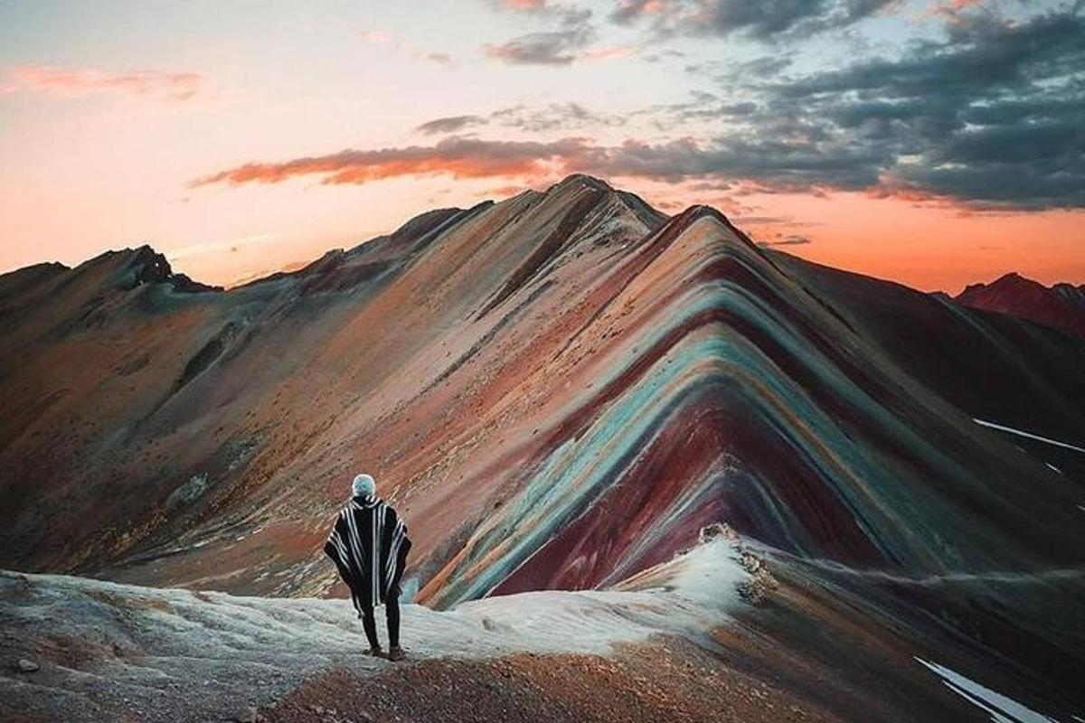 un dipinto di un uomo in piedi sulla cima di una montagna
