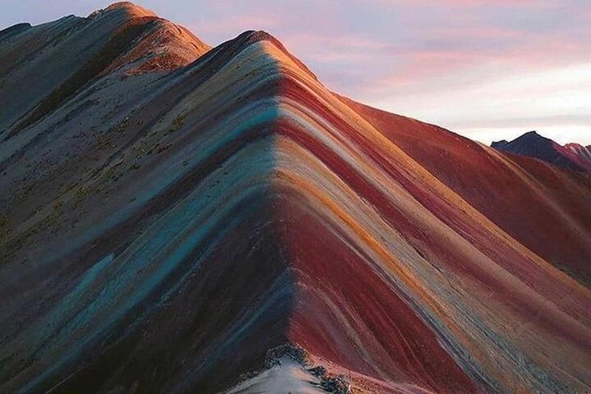 una montagna color arcobaleno con il tramonto sullo sfondo