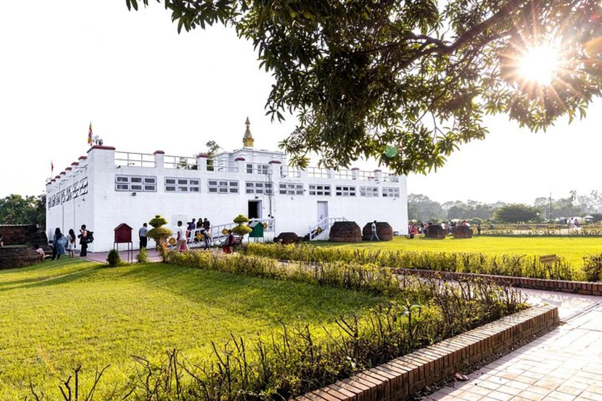 um grande edifício branco com pessoas em pé em um campo