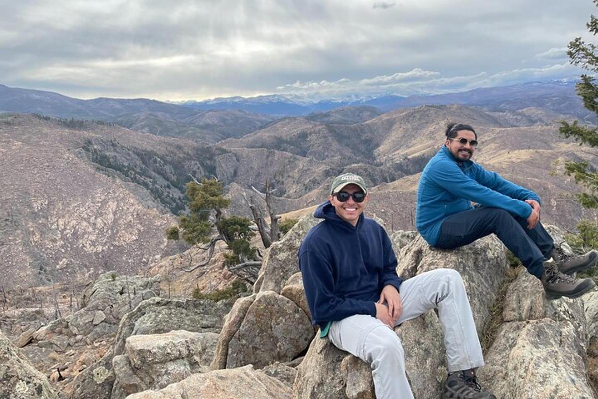 two men sitting on top of a mountain