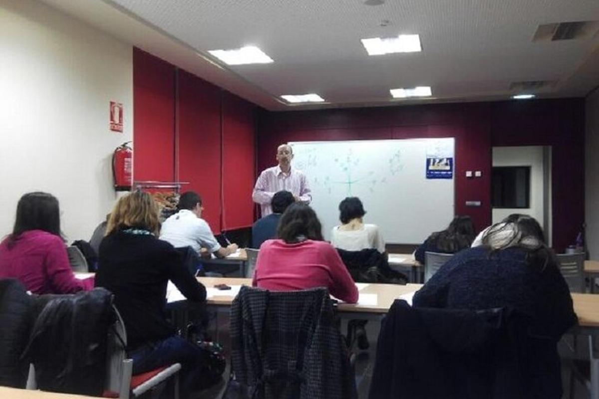 um grupo de pessoas sentadas em mesas em uma sala com uma apresentação
