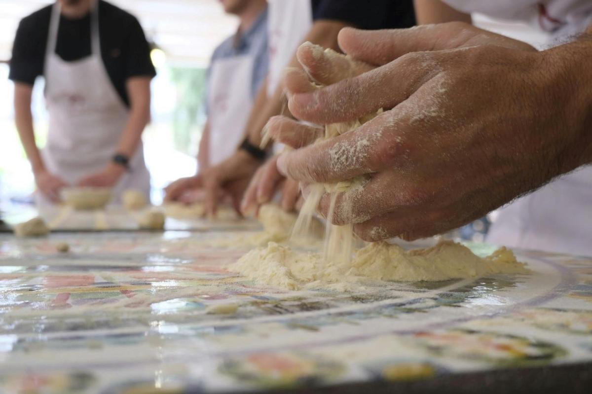 un gruppo di persone che impastano la pasta su un tavolo