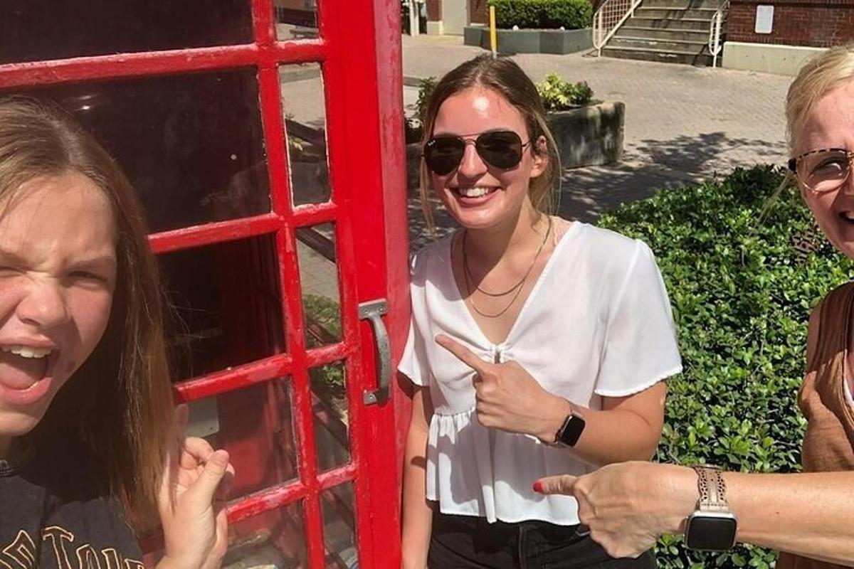 o femeie care stă lângă o cabină telefonică roșie