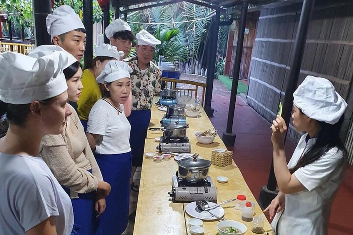 isang grupo ng mga tao sa mga chef na naka-hat na nakatayo sa paligid ng isang mesa