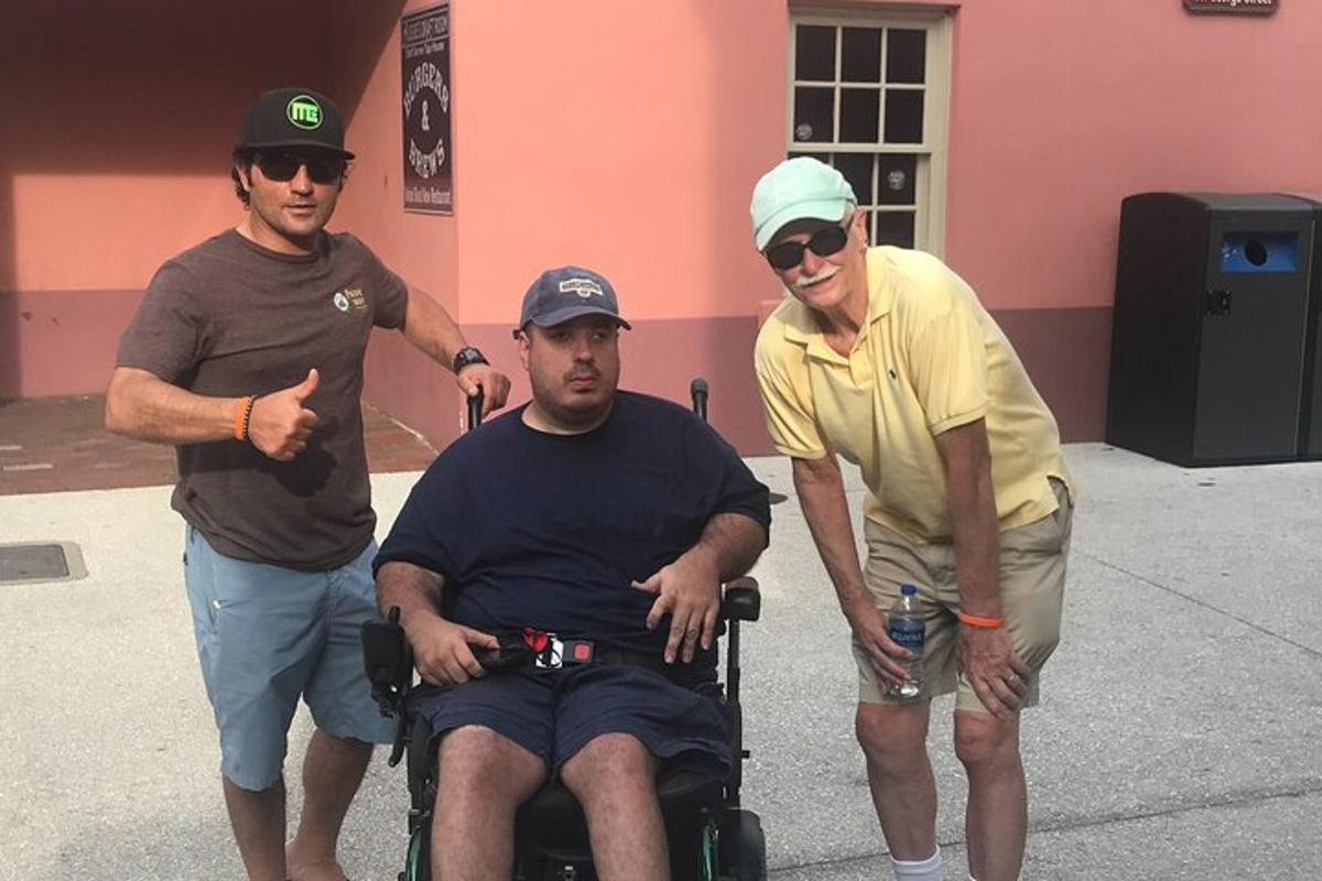 three men standing around a man in a wheelchair