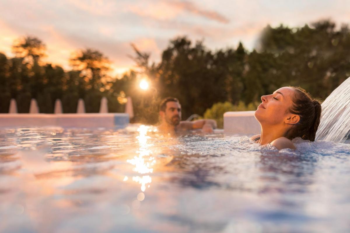 a man and a woman in a swimming pool with a surfboard