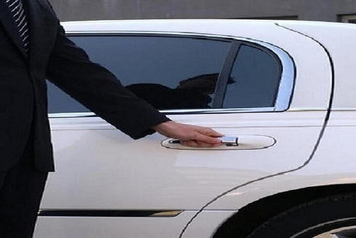 un home obrint la porta d'un cotxe blanc amb la mà
