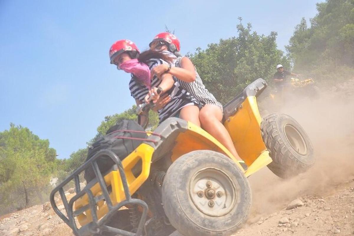 dva lidé jedoucí na čtyřkolce po nezpevněné cestě