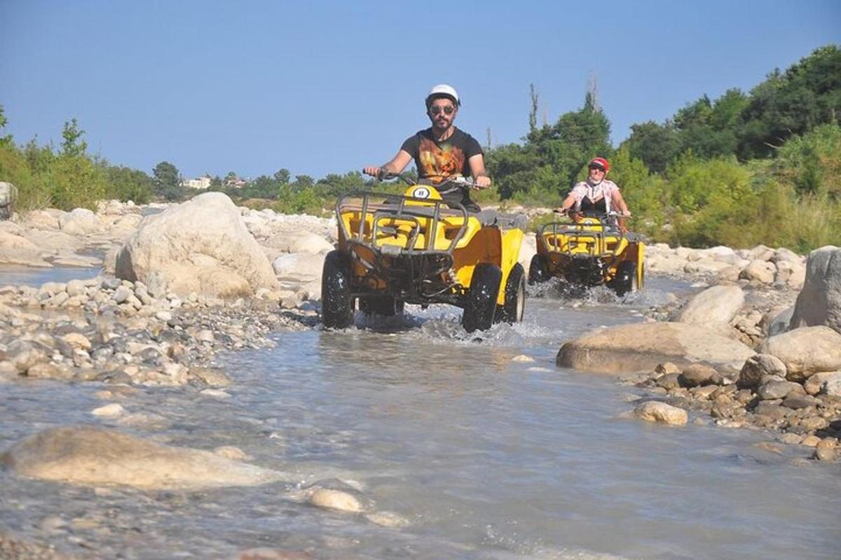 dua orang menunggang atv di dalam air di sungai
