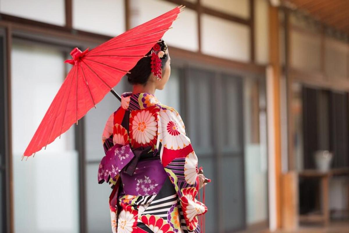 Una mujer con un kimono sosteniendo un paraguas rojo.
