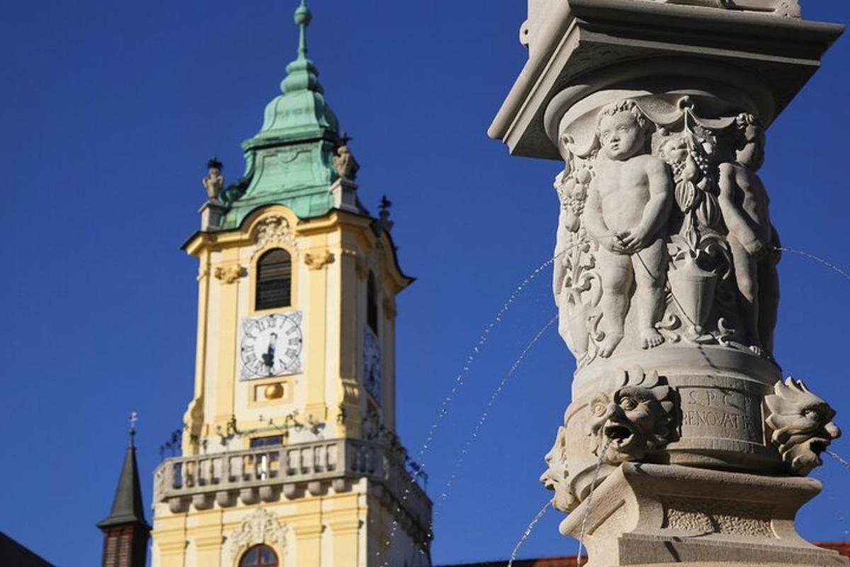 una torre dell'orologio con una statua di fronte a un edificio