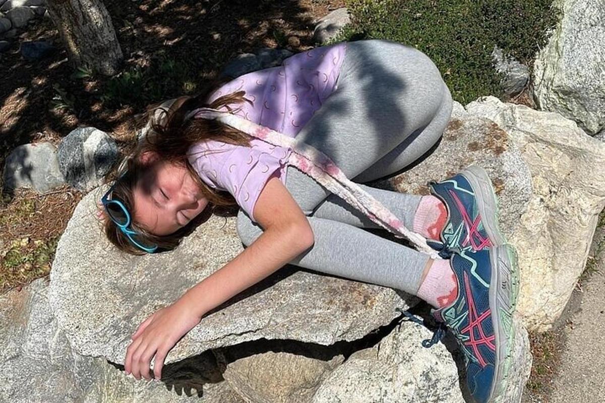a young girl is laying on a rock