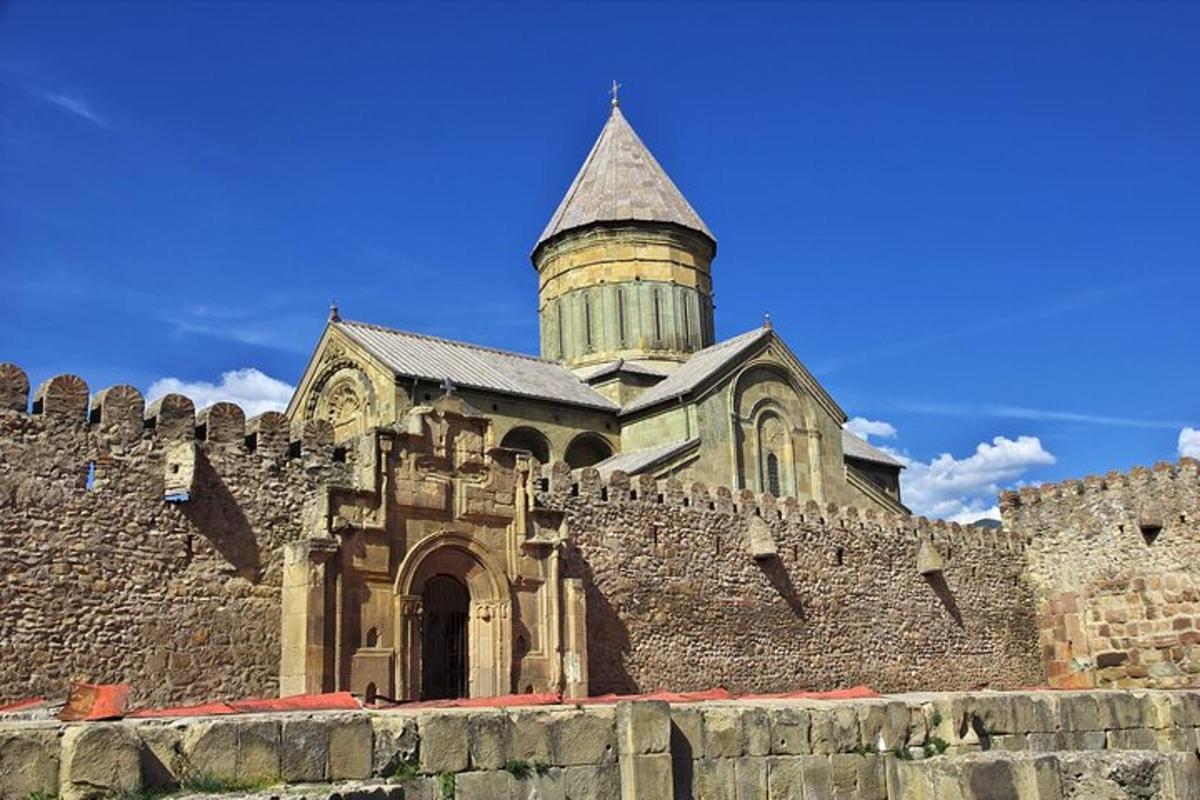 en gammel kirke med et tårn bak en steinmur