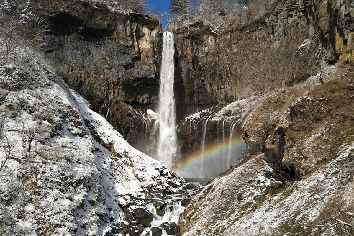 un arcoíris frente a una cascada en una montaña
