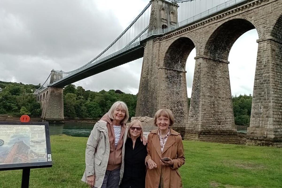 three women standing in front of a bridge