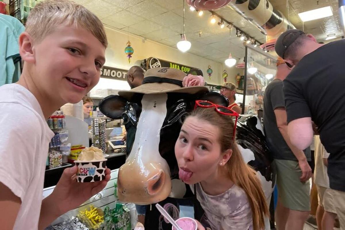 a girl sticking her tongue out next to a cow statue