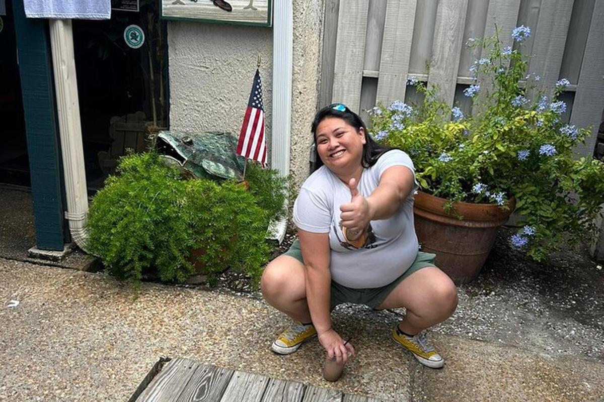a woman giving a thumbs up while kneeling in front of a house