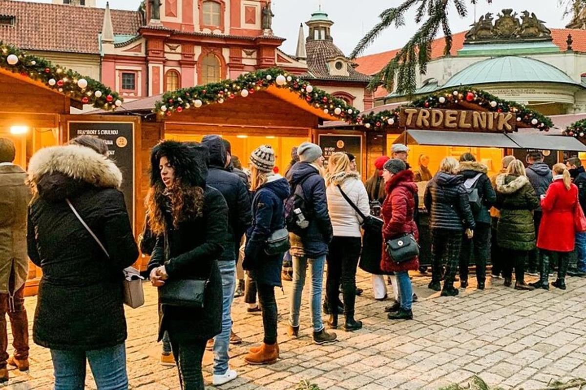 skupina ljudi, ki stojijo okoli božičnega sejma