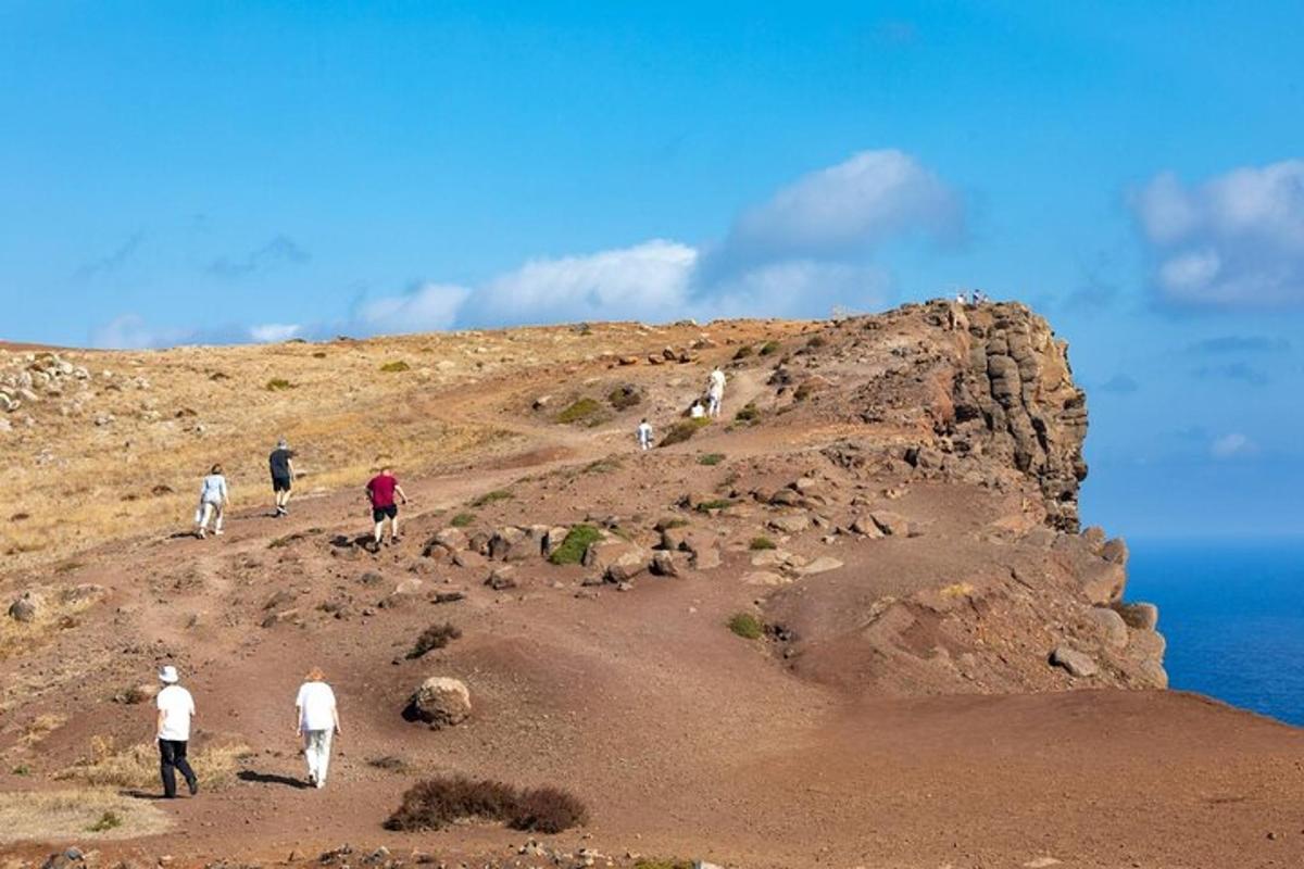un gruppo di persone che camminano su una collina vicino all'oceano