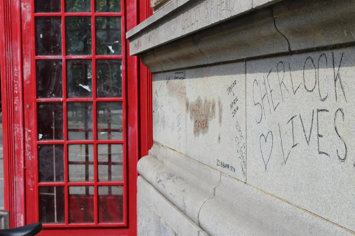 zeď s graffiti a dvěma červenými telefonními budkami