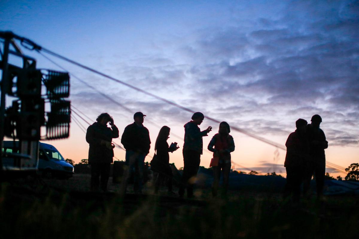 un gruppo di persone in piedi in un campo al tramonto