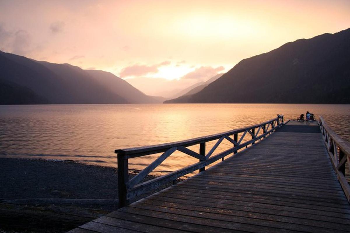 gente de pie en un puente de madera sobre un lago