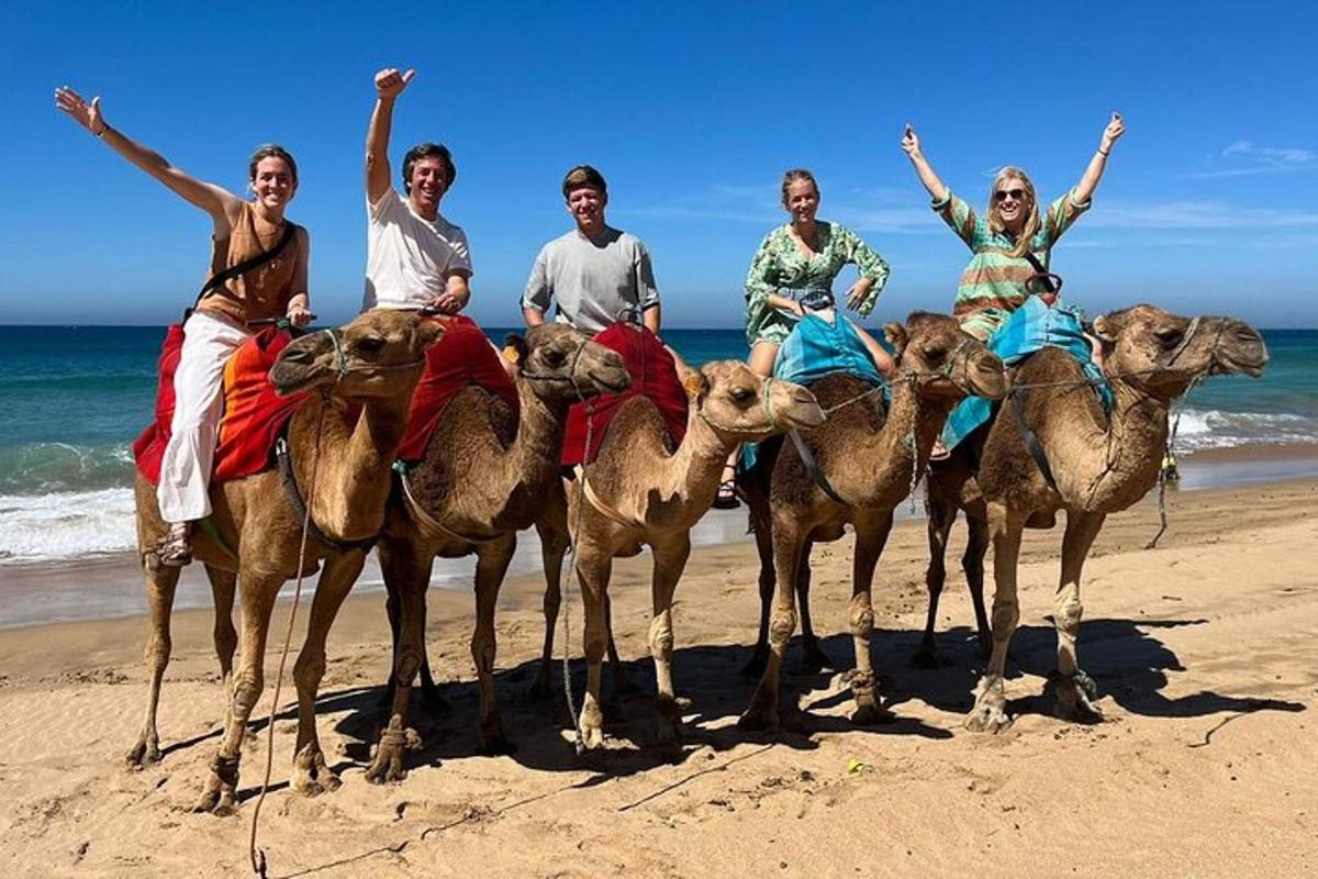 un gruppo di persone a cavallo di cammelli sulla spiaggia