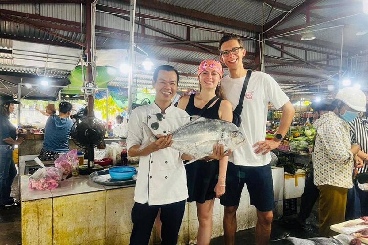 tiga orang berdiri di dapur memegang ikan