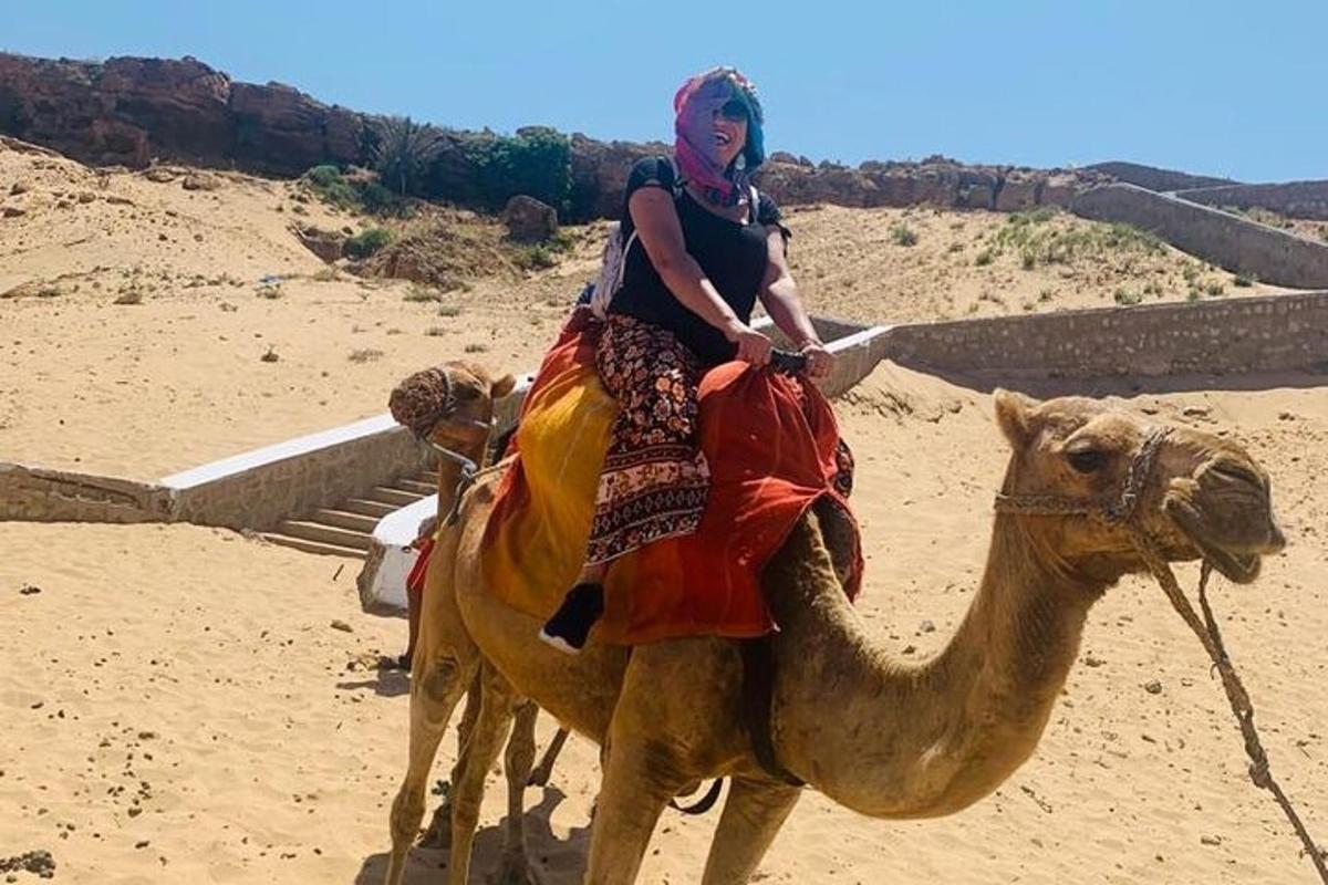 uma mulher montada em um camelo no deserto