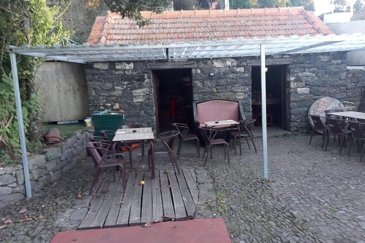 μια βεράντα με τραπέζια και καρέκλες σε ένα πέτρινο κτίριο