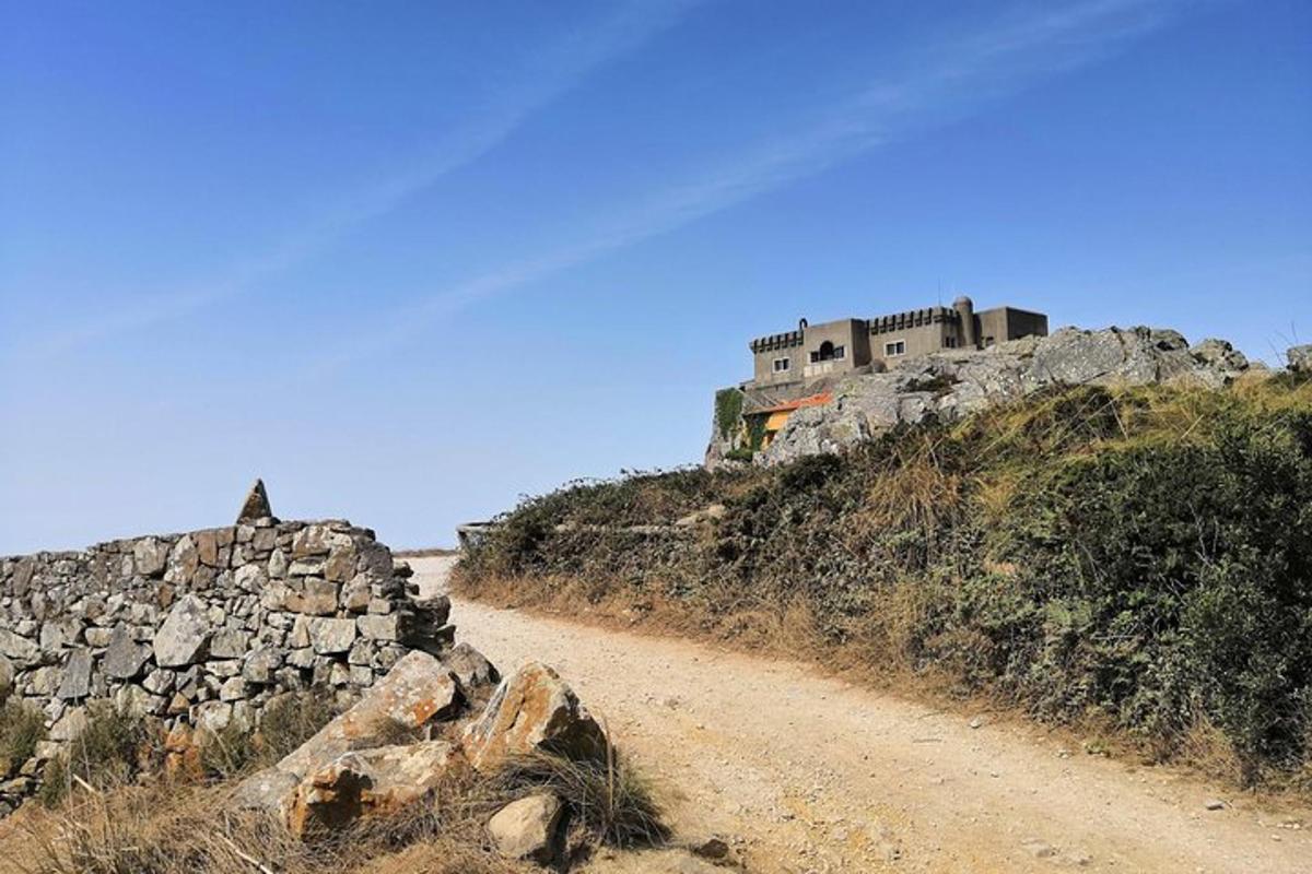 una strada sterrata con un edificio in cima a una collina