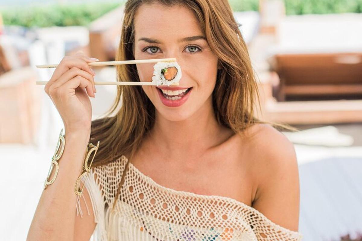 kona heldur á sushi-stykki á prjóni