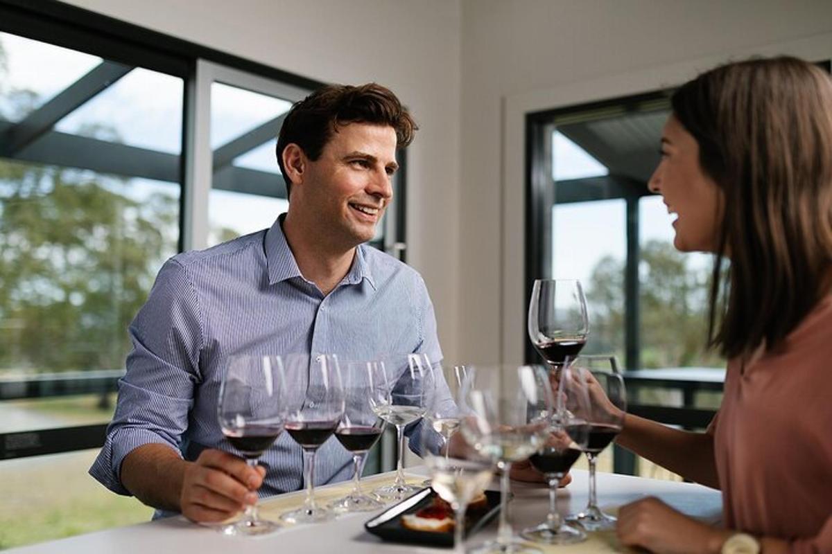 un bărbat și o femeie așezați la o masă cu pahare de vin