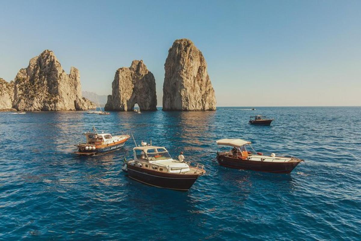 tre barche in acqua vicino ad alcune grandi rocce