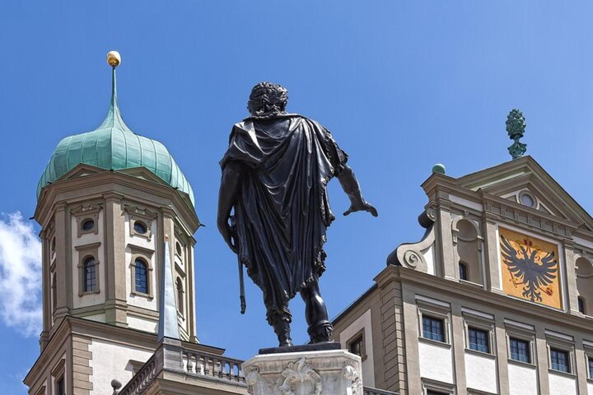 uma estátua em frente a um prédio com uma torre de relógio