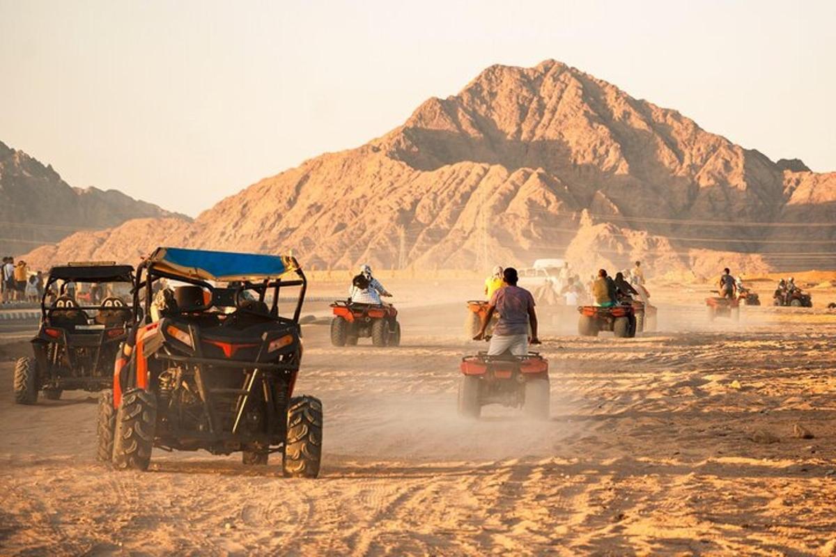a group of people riding on quad bikes in the desert